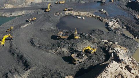 AFRICA,SOUTH AFRICA,CIRCA 2021.Aerial view. Backhoe loader excavating and dump trucks working in an open cast coal mine.Major contributing factor to climate change and global warming