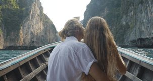 Romantic couple sitting on front of long tail boat seeing an amazing seascape of Phi Phi Islands and recording a video of beautiful view by smartphone during summer vacation travel in Phuket, Thailand