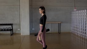 Slow motion Tracking shot, side view of caucasian slim Woman, with a fitness mat and water bottle, entering in a yoga center to start fitness routine. Stops walking and puts the yoga rug on the floor.