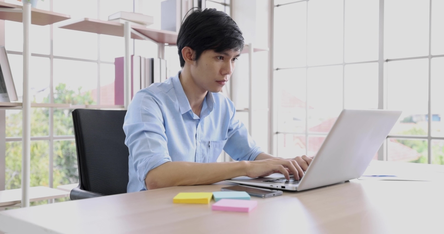 Young Asian man entrepreneur, Business owner using a smartphone and working with computer at home. | Shutterstock HD Video #1068379835