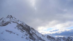 White snowy peaks and peaks in white snow against a beautiful blue sky and delicate white clouds. High mountains with white snowy peaks. Sochi, Rosa Khutor, Krasnaya Polyana. Slow motion video.