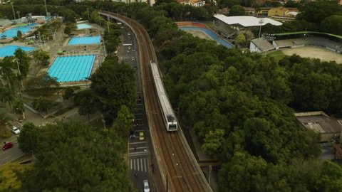Aerial Tracking Shot of Subway Train Passing Swimming Pools in Medellin.