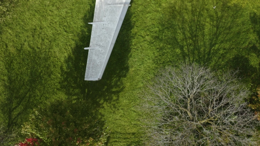 Top Down Aerial View of Abandoned Airplane in Green Field on Windy Day