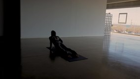 Young caucasian woman practicing morning yoga and stretching body in wide Yoga studio, withe wide windows, female Pilates professional doing breathing exercise on a mat. Steadicam shot.