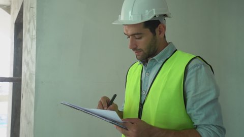 Builder,Building young caucasian man contractor, engineering holding clipboard, wear jacket inspect the construction and renovation, check defect of apartment, home on site. Engineer worker concept.