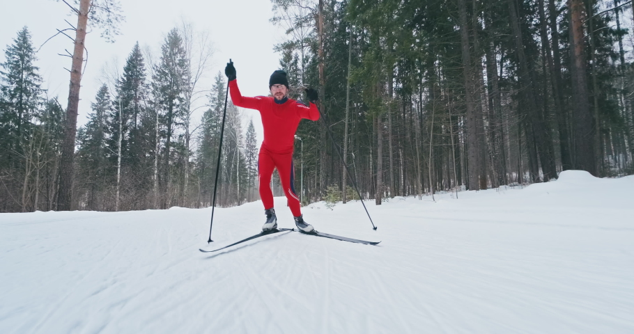 Cross country ski workout. Young man in red ski suit works out and runs on the cross country ski track in a forest Royalty-Free Stock Footage #1068396311