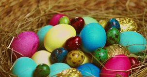 Colourful Easter eggs lying on hay rotating, close up video. Springtime religious christian holiday