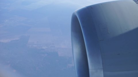 Closeup of the turbine of a plane flying with a view of landscape 