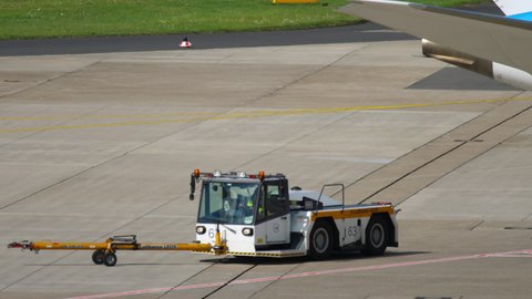 DUSSELDORF, GERMANY - JULY 23, 2017: A tow tractor pulls up to the plane at the airport. Airport traffic