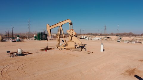 Cinematic close up forward aerial fly over of an active oil and gas pumpjack.  Located on the Permian Basin this footage was shot with clear skies on a sunny afternoon.   