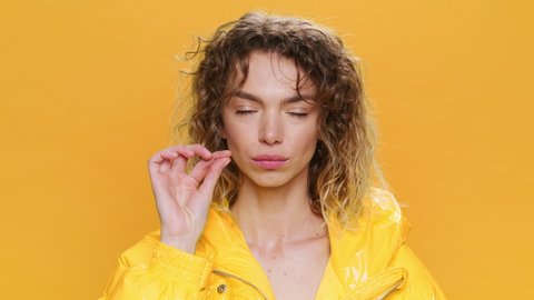 Portrait Happy Young Woman Smiles Keep Secret zipping locking mouth silence Looks at Camera. Glamorous Girl Curly Hair in Yellow Jacket on Yellow Background. Fashion. Monotone Positive Emotions People
