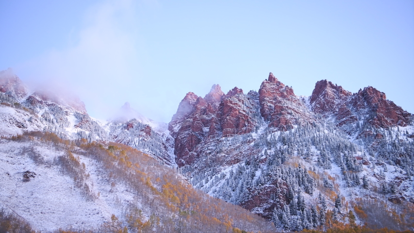 Landscape zoom zooming in Maroon Bells sunrise view in Aspen, Colorado red elk mountains with rocky mountain and snow in late autumn with winter mist fog cloud covering