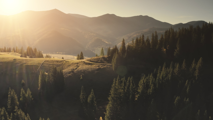 Sun over mountain ridges aerial. Pine forest at mount village. Autumn nobody nature landscape. Cottages at burnt grass farmland. Rural road at Alpine field. Countryside holiday at Alps, France, Europe | Shutterstock HD Video #1068408449