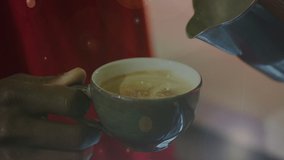 Animation of floating particles with hands of a man pouring milk into cup of coffee. independent business concept, digitally generated video.