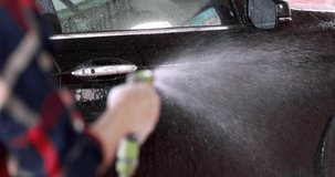 Black car wash water spray to cleanse the dirt car wash yourself at home concept  4K video 