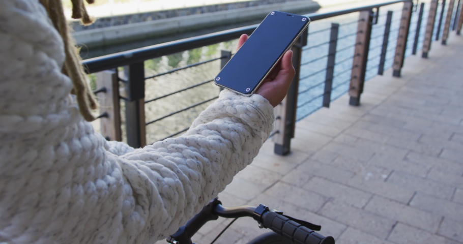 Mixed race man with dreadlocks riding a bicycle in the street using smartphone. digital nomad, out and about in the city.