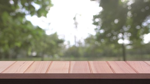Close up Top Wood table bar and nature tree bokeh blurred background. At morning time and beautiful nature sun light, Top wood table space area for products shows. 4096x2304. 4K UHD. Video Clip