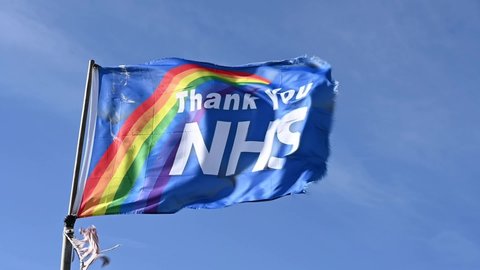 Lancing, West Sussex, UK, February 18, 2021. Thank You NHS Flag with Rainbow design fluttering proudly in the breeze in slow motion. 