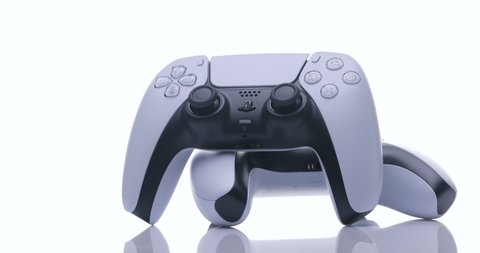 NEW YORK - February 27, 2021: Close up view of 2 controllers from new console with light. Two joysticks from Sony PlayStation 5 TV game console spin on a white background.