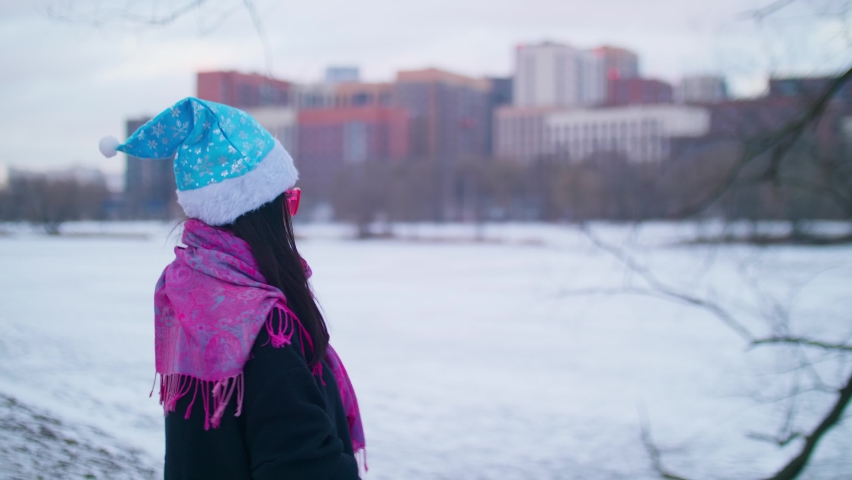 Side view of brunette wearing funny santa hat. Nice winter afternoon