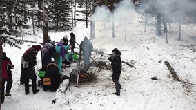 Aerial video from a drone overlooking a winter landscape in the Ural forest. Tourists at a lunch break, basking around the campfire on a hike. Aygir, Republic of Bashkortostan, Russia.