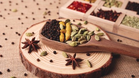 Mix of Indian spices for Indian cooking in wooden spoon. Curry Masala for making hot spicy curry whole turmeric, cardamom, black pepper in Indian spice box Kerala India Sri Lanka.
