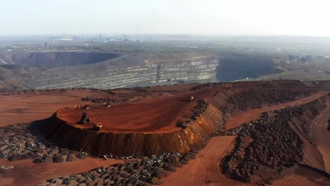Huge mounds of waste iron ore near the quarry. Belaz trucks driving in mining factory, mine quarry in Ukraine