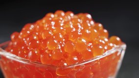 Close-up video of red caviar on black background