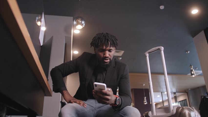 black man waiting for departure, upset talking on the phone