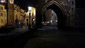  street light lamp of a stone bridge tower on Charles Bridge and in the background a railway passes in the old town of Prague at night
