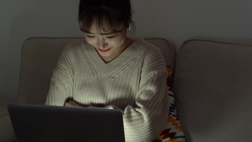 A young Asian woman watching a laptop display at night