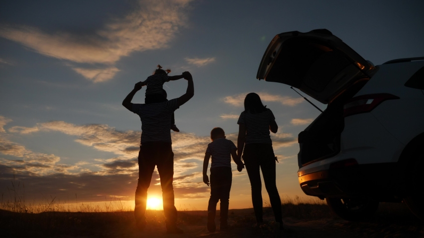 Happy family children kid together standing next to car watching the sunset silhouette in park. family travel dream concept. happy family stand with sunlight their backs watching in the park journey | Shutterstock HD Video #1068440585