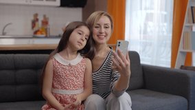 Happy mother and daughter have a video call with their loved ones on their mobile phone. Remote communication concept.