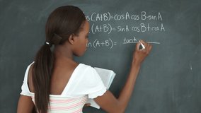 Animation of floating numbers over a girl writing on a blackboard. education and learning concept digitally generated video.