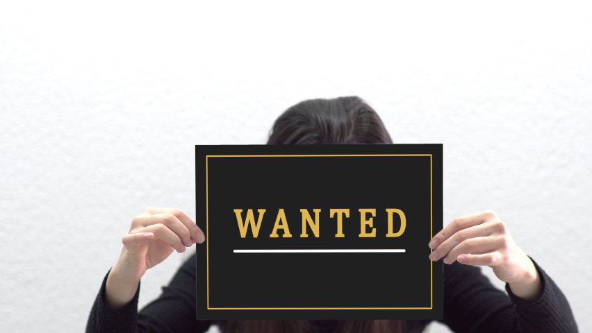 Conceptual message "Wanted" on canvas frame label hold by beautiful girl smiling at camera