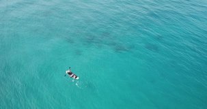 Summer time by the sea. Aerial view of child on paddleboard. Cute child learning on a paddleboard. Stabilized 4K video.