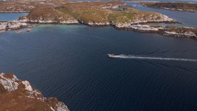 Fisher boat on the norwegian coast. Small ship cruising through beautiful islands in shallow water. Aerial drone video at Froya, Norway.
