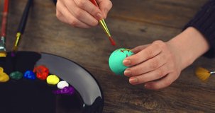 Celebrating Easter. Close up video of artist's hands painting on egg. Preparations for christian religious holiday