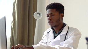 Young african american male doctor working on laptop in clinic