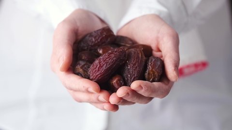 Woman Holding a Heap of Date Fruit Toward Camera. The Food Mostly Eating in Ramadan. Daylight, Close Up Slow Motion Shot. 4K Resolution. 