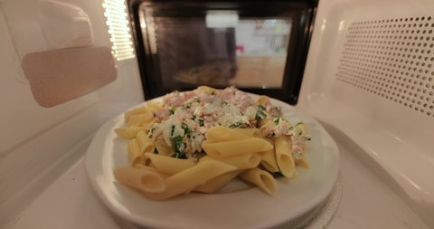 Heating up food in a microwave viewed from inside the back, plate of pasta with salmon