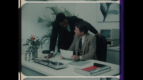 1980s Chicago, IL. Business Men discuss Proposal in Corporate Business office. Retro 80s Office Interior with Retro Computer Technology. 4K Overscan of Vintage Archival 16mm Film Print 