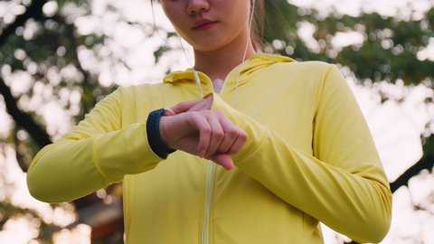 Athletic female measuring heart rate on a smartwatch while resting after workout running at the street in urban. Athlete sport running workout concept.