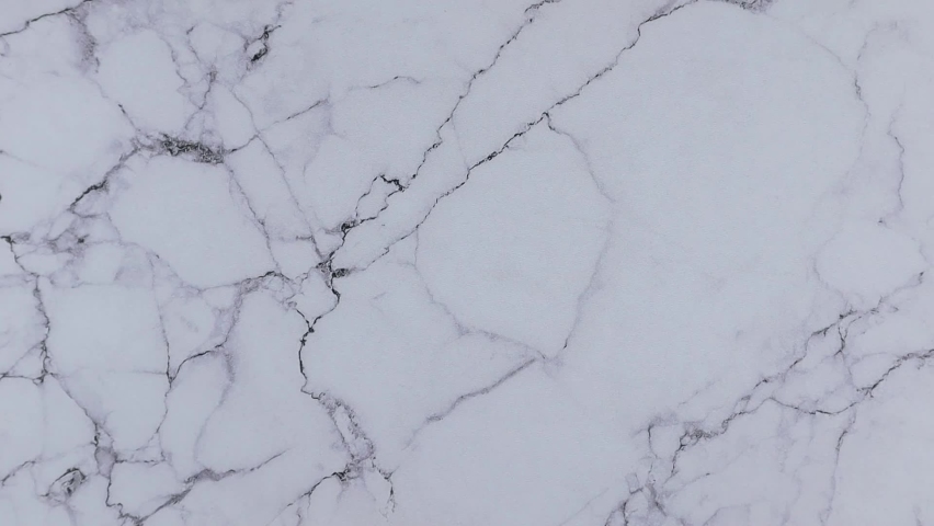 Beauty concept with colorful alphabet letters on wooden cubes centered between top and bottom borders of additional alphabet blocks on a marble background. Stop motion, top view