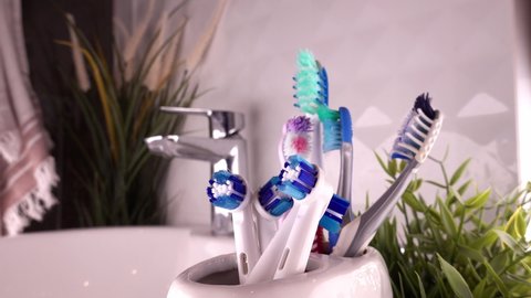 Brand New Electric and Worn Out Manual Toothbrushes For Family of Four In Bathroom Dolly Shot Close Up