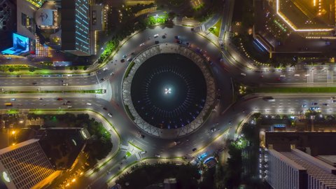 Aerial Birds Eye Overhead Top Down View hyperlapse of busy car traffic on roundabout around Selamat Datang monument in Jakarta at night, motion time lapse hyper lapse - Jakarta, Indonesia in 2021