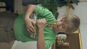 Sweet little boy with Down Syndrome keeps bowl of salad in domestic kitchen. Vertical format video