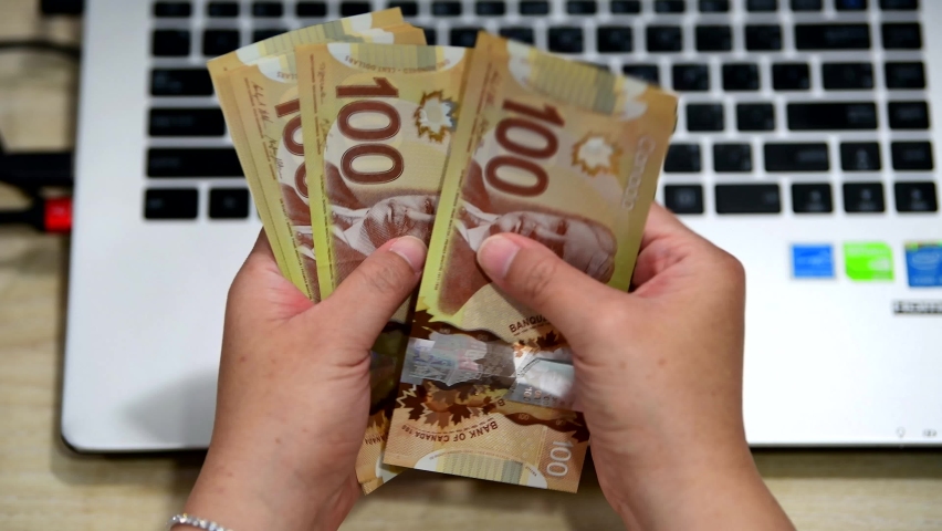 VANCOUVER - SEPTEMBER 2,2018 :Woman counting many Canadian 100 bills after receive money from online businesses	
