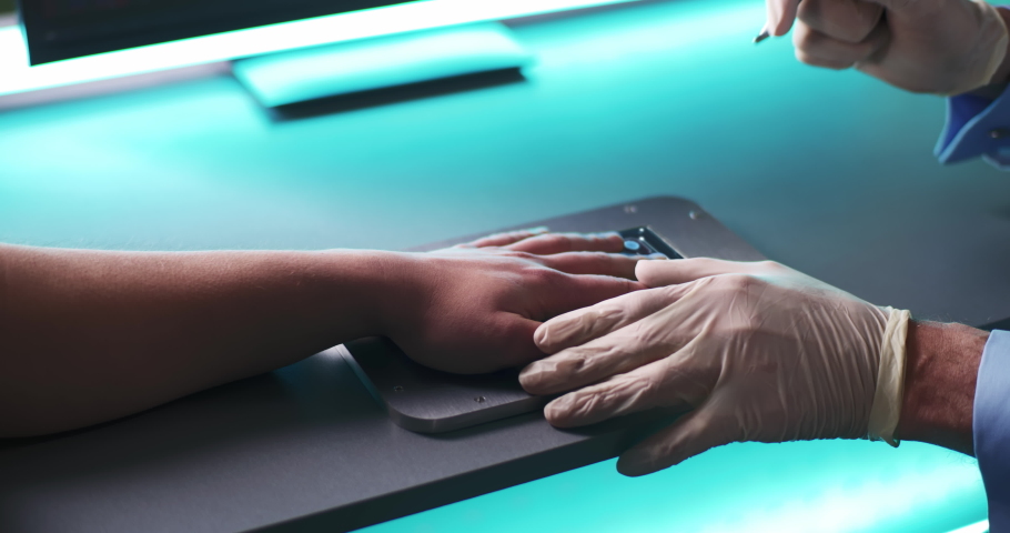 From above anonymous doctor in gloves injecting futuristic red RFID microchip into hand of patient on scanner in lab Royalty-Free Stock Footage #1068495542
