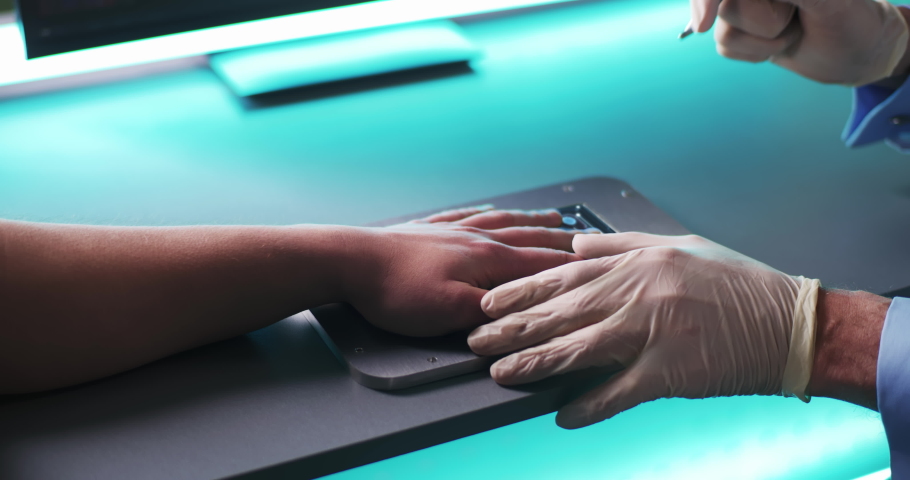 High angle of anonymous medical practitioner in gloves using modern tool to implant blue RFID microchip into hand of patient over table with futuristic scanner in laboratory Royalty-Free Stock Footage #1068495545